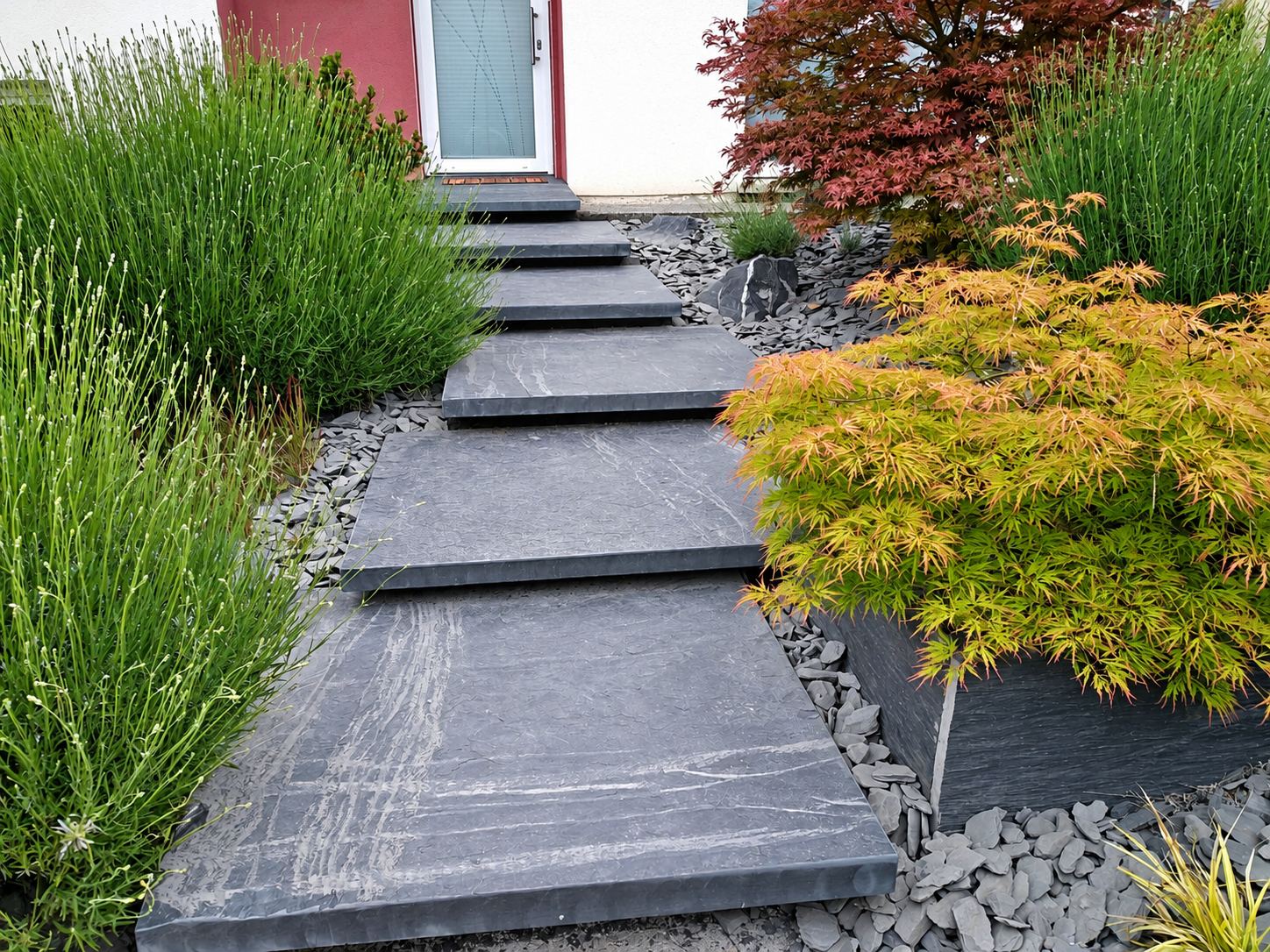 Un escalier de larges dalles d'ardoise grise mène à une porte, bordé de lavande, d'érables du Japon et de schiste concassé.